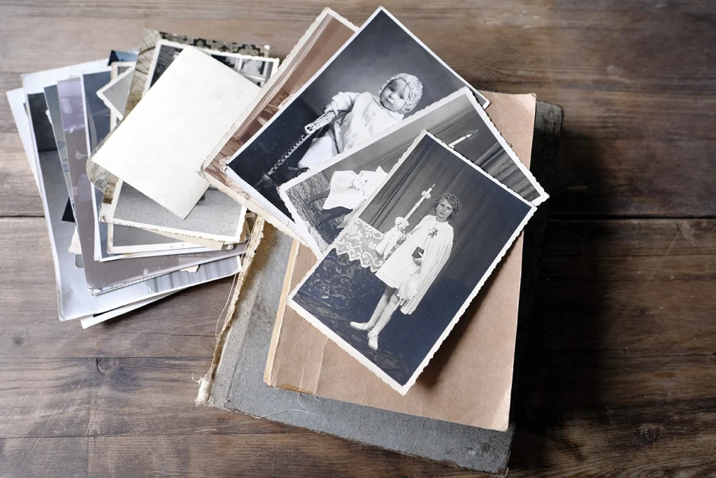 A stack of old photos fanned out on a wooden table.